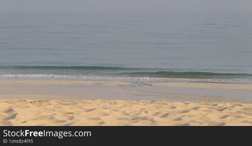 Calm Shoreline. Gentle waves roll onto a quiet sandy beach, creating a peaceful and undisturbed landscape