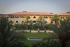 A Grand Building With Arched Windows And A Red-tiled Roof Stands Majestically. The Front Garden Royalty Free Stock Image