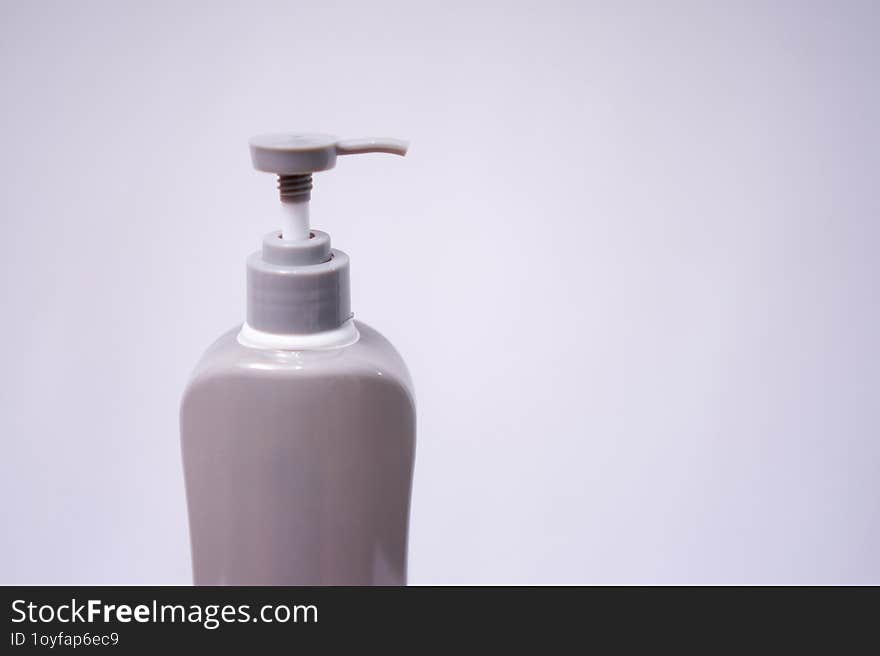 Selected focus photo of a gray and white plastic body lotion bottle isolated on white background