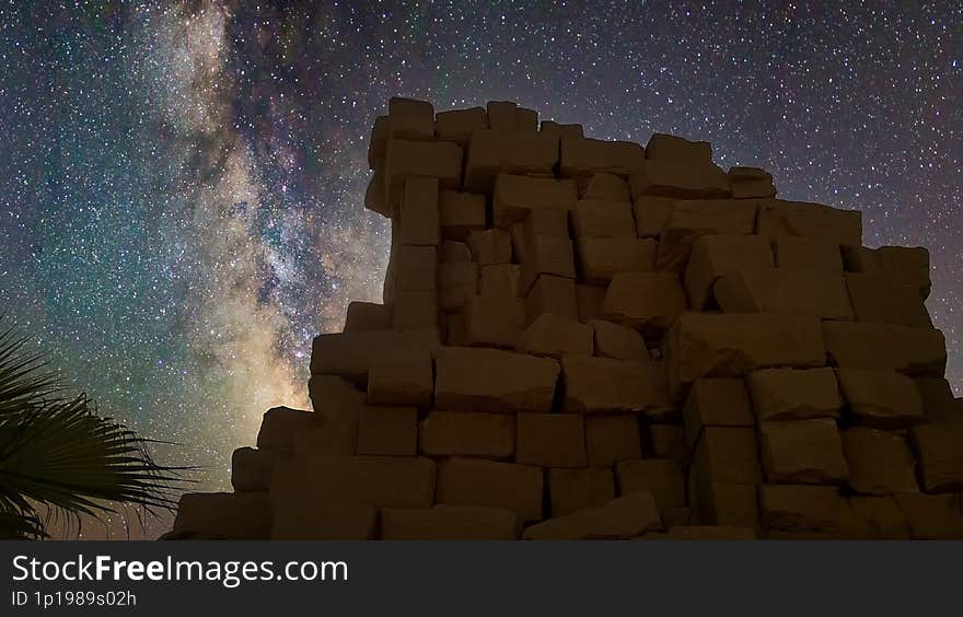 Starry sky over Egypt with old wall of a temple in the foreground