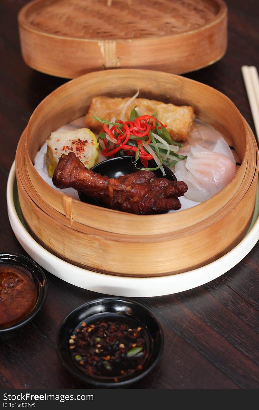 A vibrant plate featuring a selection of Asian dumplings and steamed white rice, complemented by a serving of red char siu pork, g