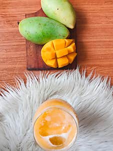 The Sweet And Fresh Mango Juice Was Served In A Fancy Glass, While Next To It Was 1 Peeled Mango And 2 Others Still Intact. Royalty Free Stock Photo