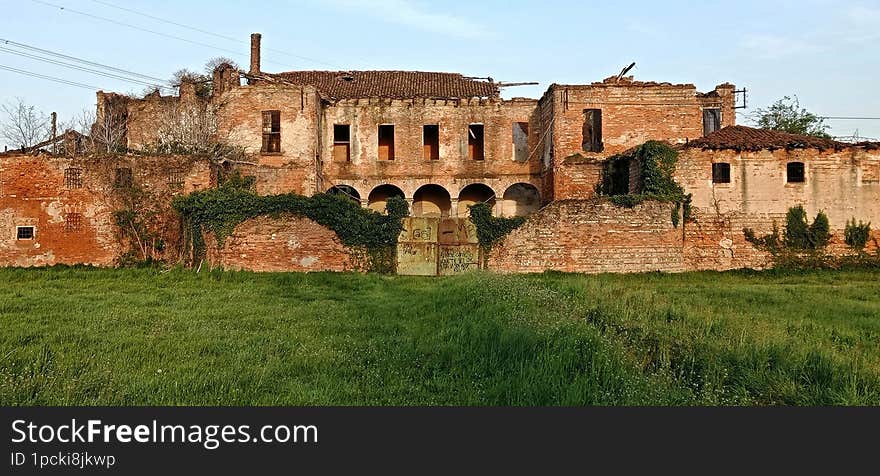 Cascina Torriana, Cernusco sul Naviglio - March 2023: ruins of the old abandoned farmhouse, a green meadow in the foreground.