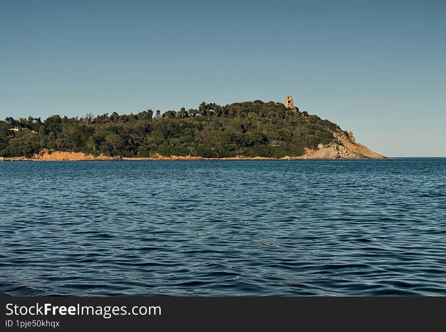 Tortol�, Sardinia, Italy: July 2016 - Cape San Gemiliano and the hispanic tower seen from the beach and the blue Mediterranean Sea