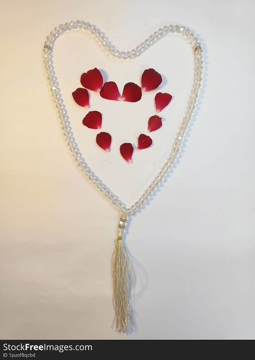 A beautiful and symbolic image featuring a heart-shaped tasbih (prayer beads) adorned with delicate red rose petals. This image re