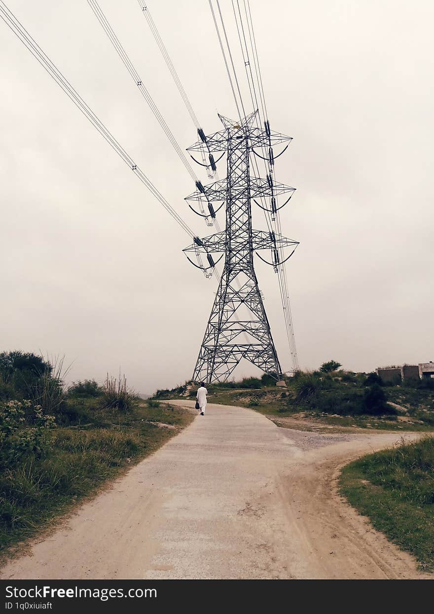 A man walking on village road in summer electrity tower in background