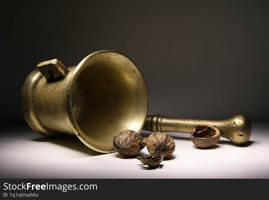 A mortar and pestle and two walnuts are lying on the table