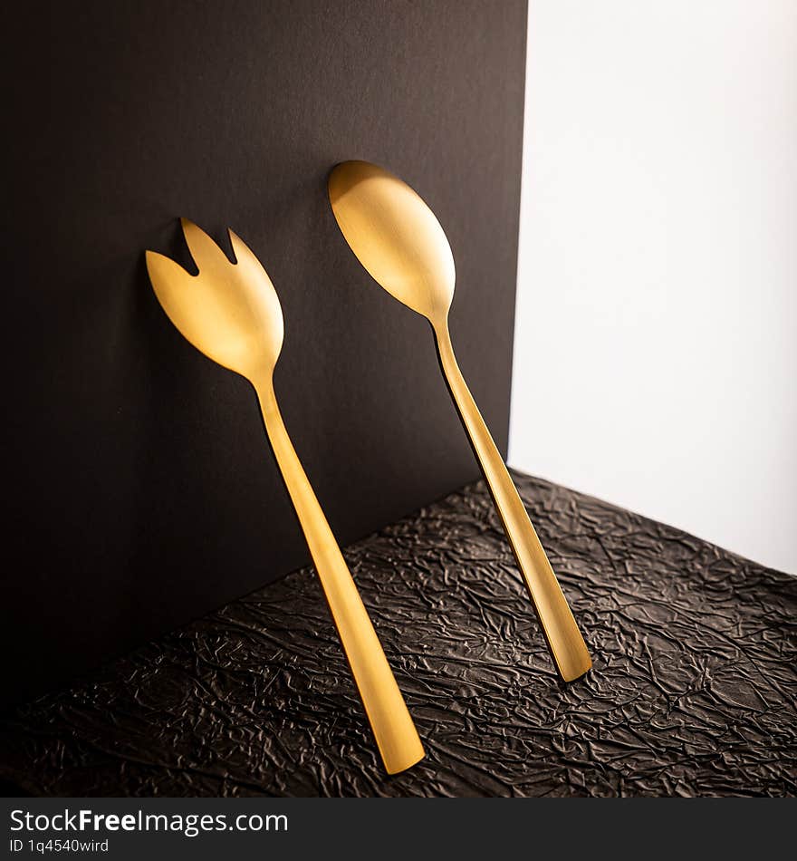 Elegant Golden Spoon and Fork on a Minimalist Black Background