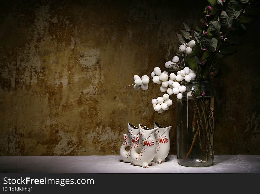 A bouquet of snowberries against an unpainted wall and three ceramic fish