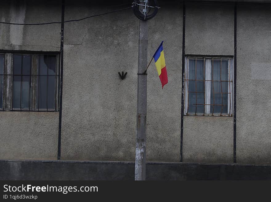 Romanian flag, next to old arhitecture building with a broken glass. The flag ,suggesting a little hope