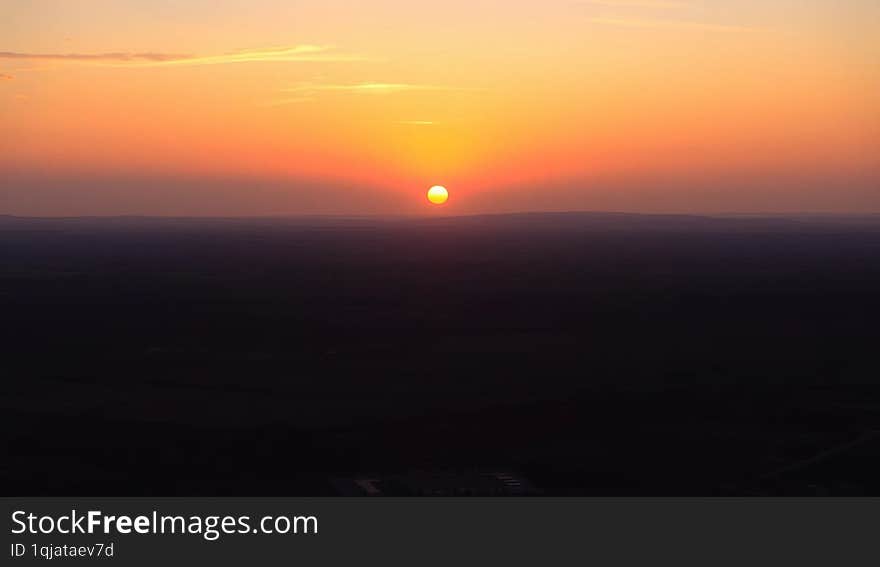 a vibrant sunset as seen from the surface of the Earth, with the horizon stretching across the frame, showcasing the warm, golden