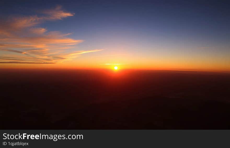 a vibrant sunset as seen from the surface of the Earth, with the horizon stretching across the frame, showcasing the warm, golden