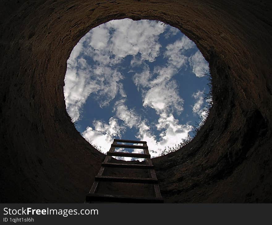 Wooden staircase leading from the earth well up to the blue sky