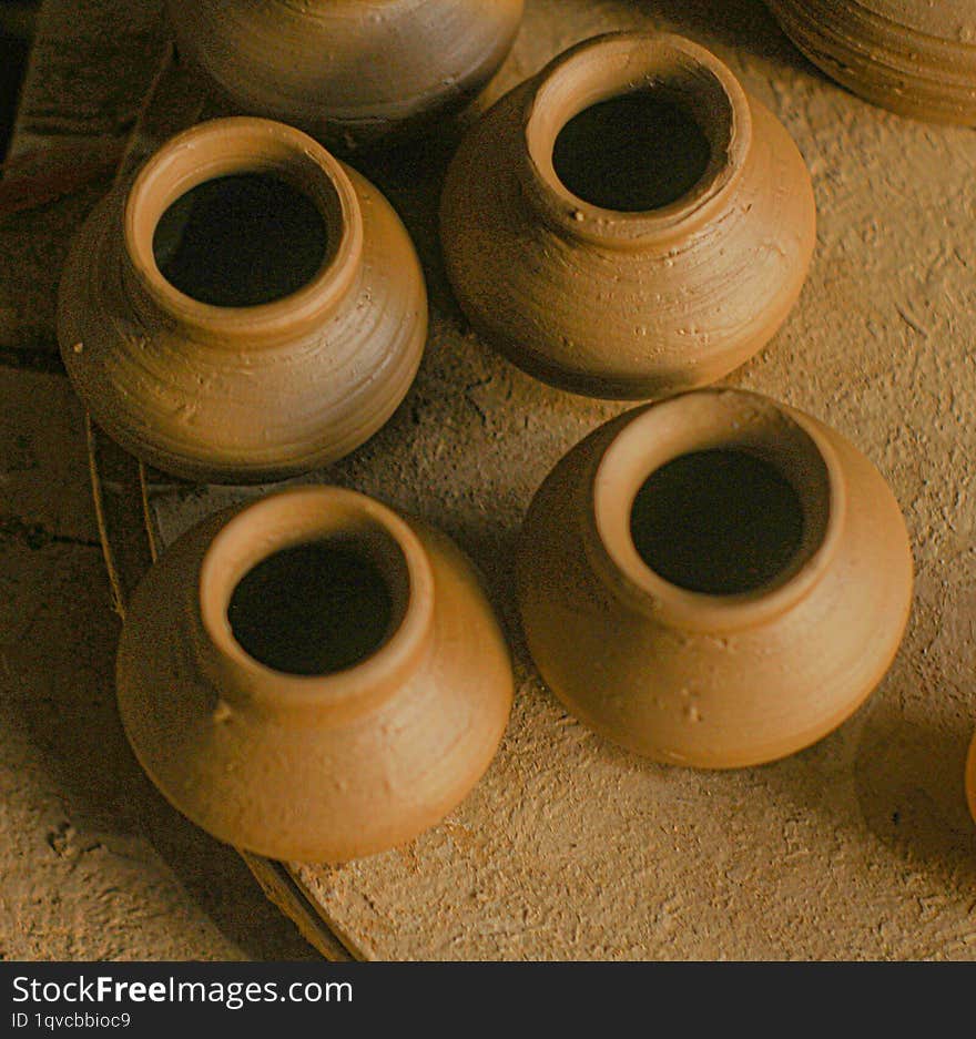 A close-up of several small, unglazed clay pots arranged in a semi-circle. The pots are a warm, reddish-brown color with visible f