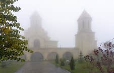 Church Yard With Grass, Bushes And Trees, Tiled Path, Bell Tower And Church In The Fog Royalty Free Stock Image