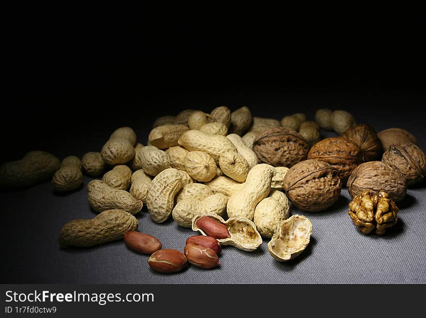 Unshelled peanuts and walnuts on a dark background