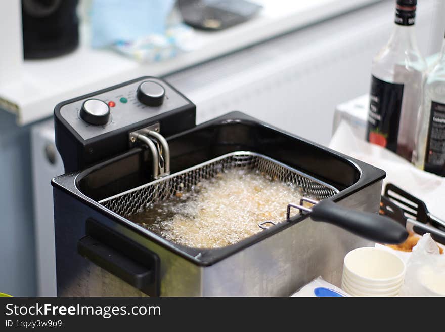 Golden, crispy chicken nuggets frying in hot oil, bubbling and sizzling to perfection. The mouthwatering aroma fills the air as th