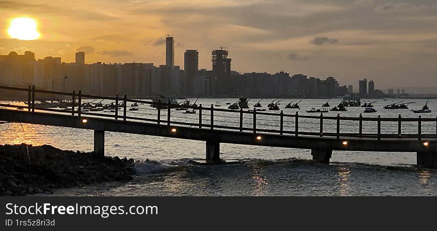 Beautiful sunset of the sea with a bay of ships, boats and a pier.