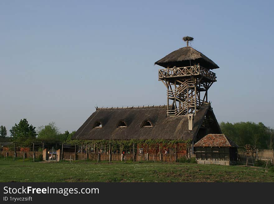 An old barn in a field with a watchtower.