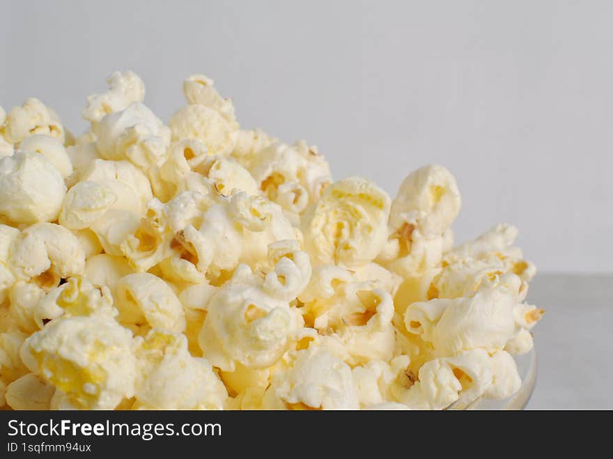 Golden and crispy popcorn in a glass bowl with close-up view,  on white background.