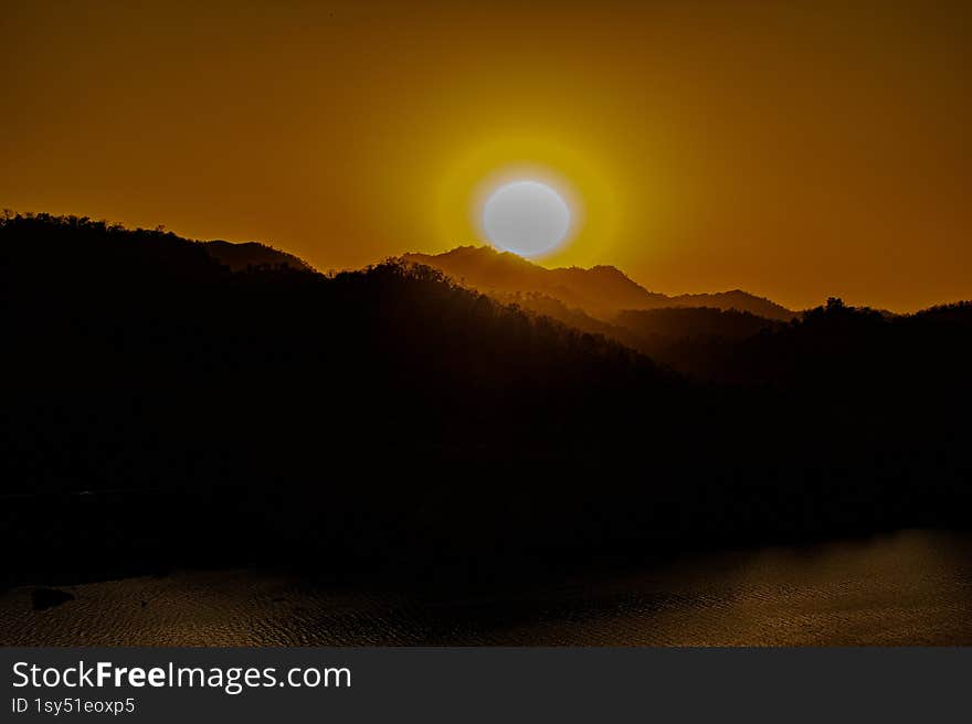 Golden Sunset Over the Mountains � A Serene Evening Glow. The sun sets gracefully behind the silhouette of the mountains, casting