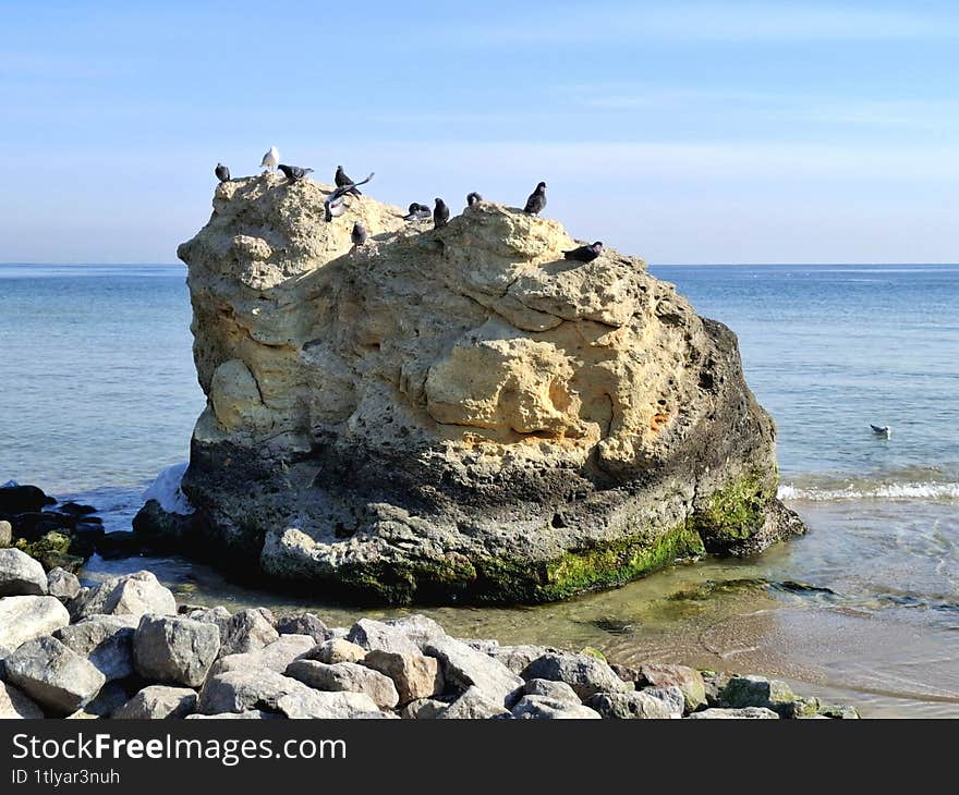 yellow rock in the water. view of a large yellow rock against the background of the sea and blue sky