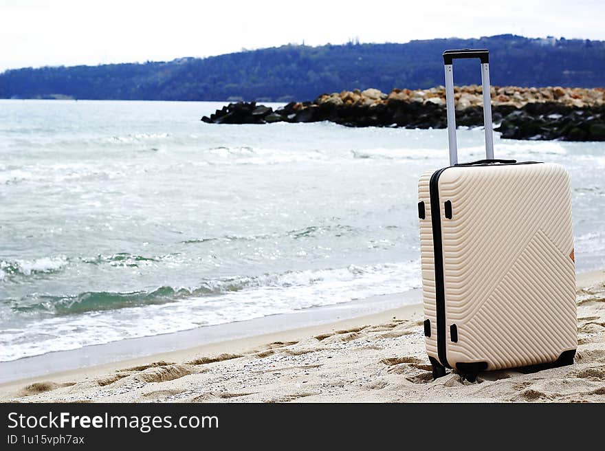 A suitcase stands on a sandy beach by the sea background. Perfect for travel, vacation, and adventure concepts. Space for text.