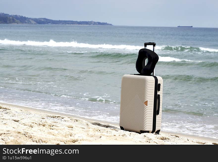 A suitcase stands on a sandy beach by the sea background. Perfect for travel, vacation, and adventure concepts. Space for text.