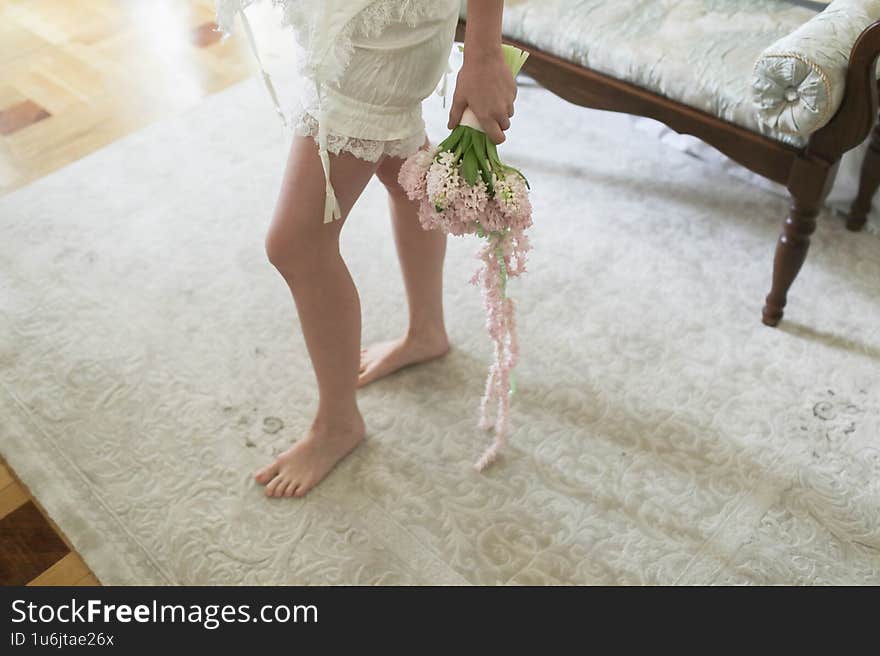 A very beautiful bride is holding a wedding bouquet during her preparations. Close-up.