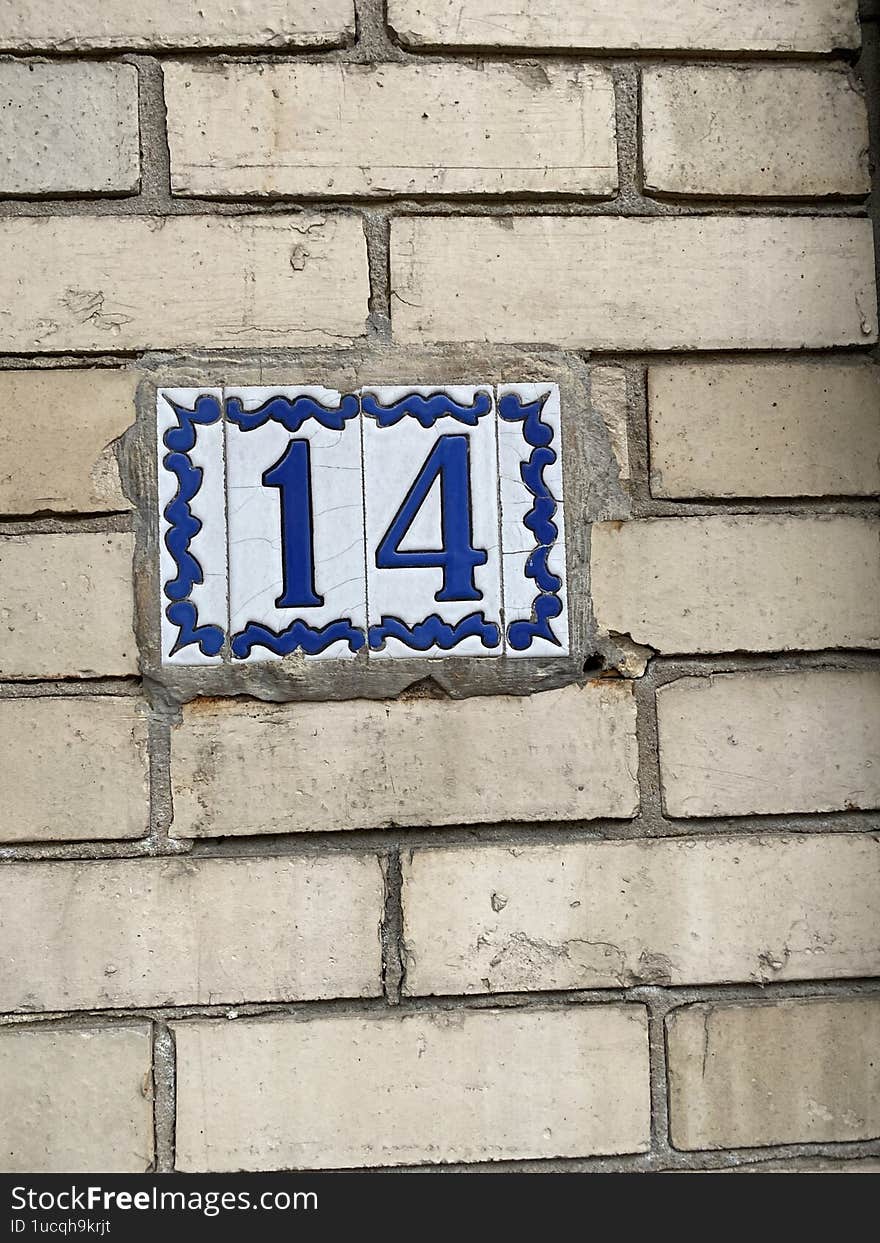 The house number with the numbers fourteen, or in numerical expression 14. Judging by the appearance, the numbers are made of a material - ceramics and painted blue.