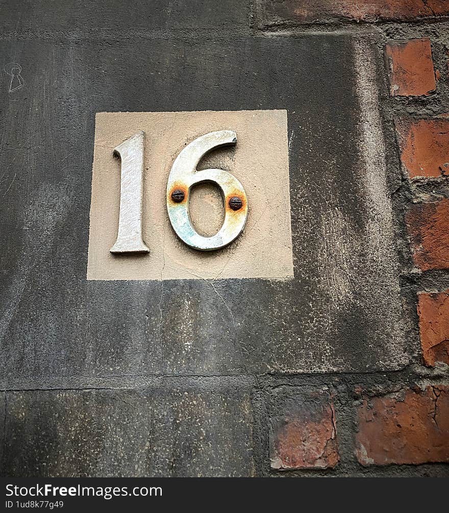 The house number with the numbers sixteen, or in numerical expression 16. material - metal. old rusty screws