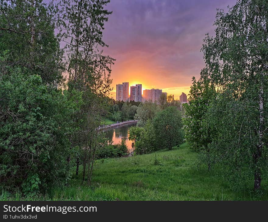 A vibrant crimson and orange sunset painting the sky above the city