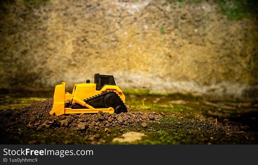 South Minahasa, Indonesia - January 3, 2023: a yellow bulldozer toy is leveling the ground