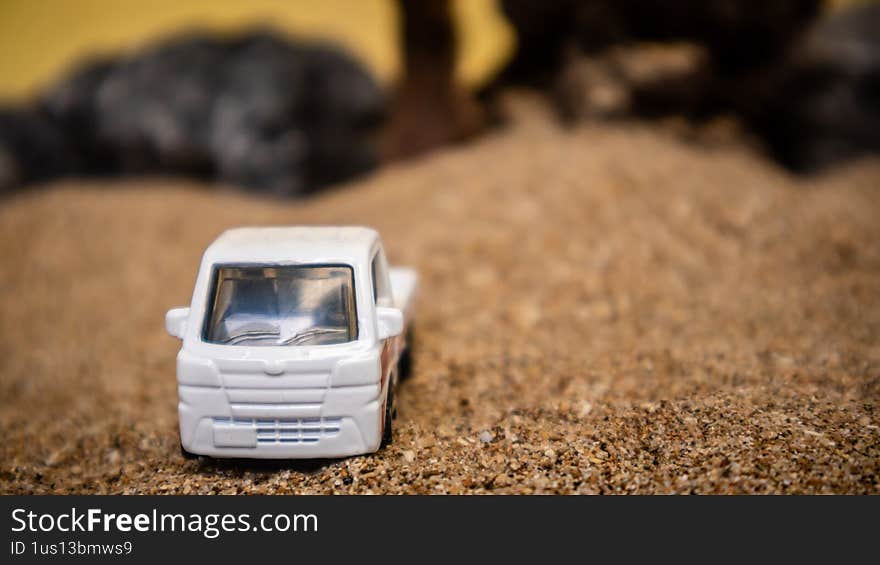 South Minahasa, Indonesia - February 2, 2023: Toy car in the sand on a yellow background looks like afternoon