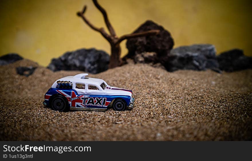 South Minahasa, Indonesia - February 2, 2023: Toy car in the sand on a yellow background looks like afternoon