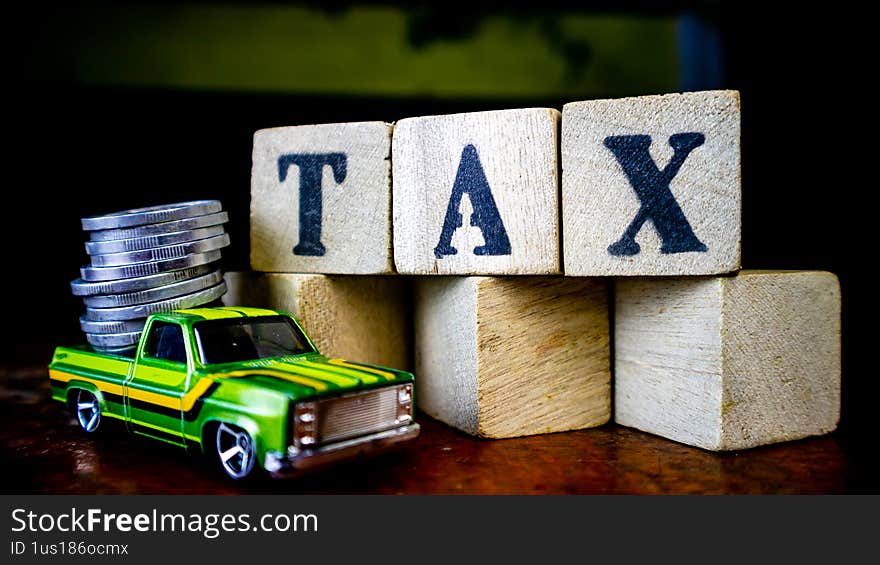 tax writing on wood with coins on it and a toy car in the foreground