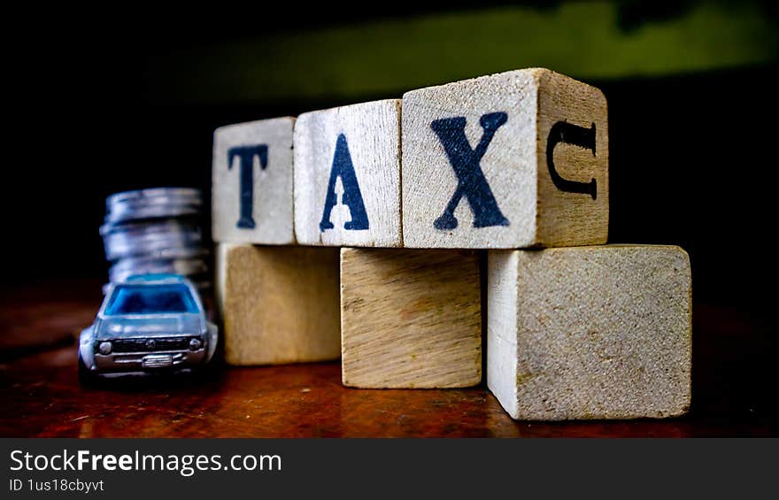 tax writing on wood with coins on it and a toy car in the foreground