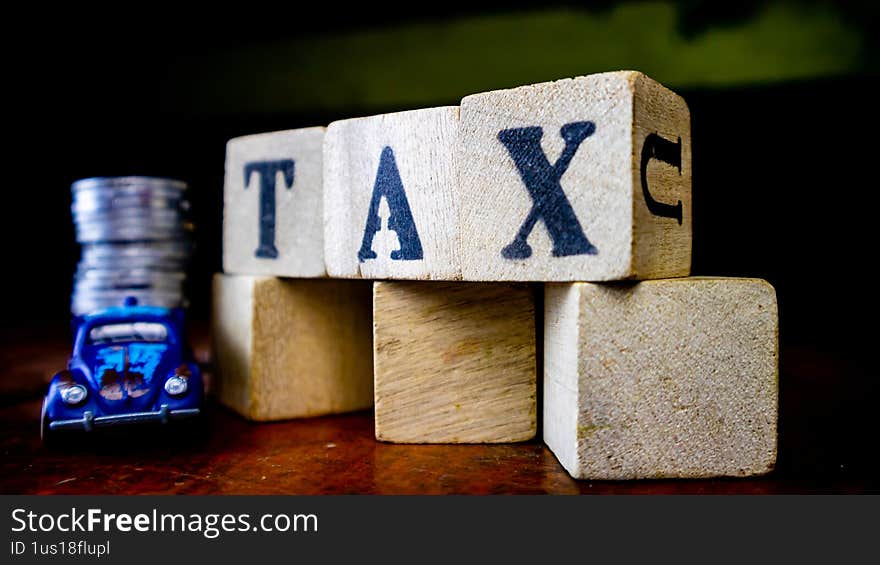tax writing on wood with coins on it and a toy car in the foreground
