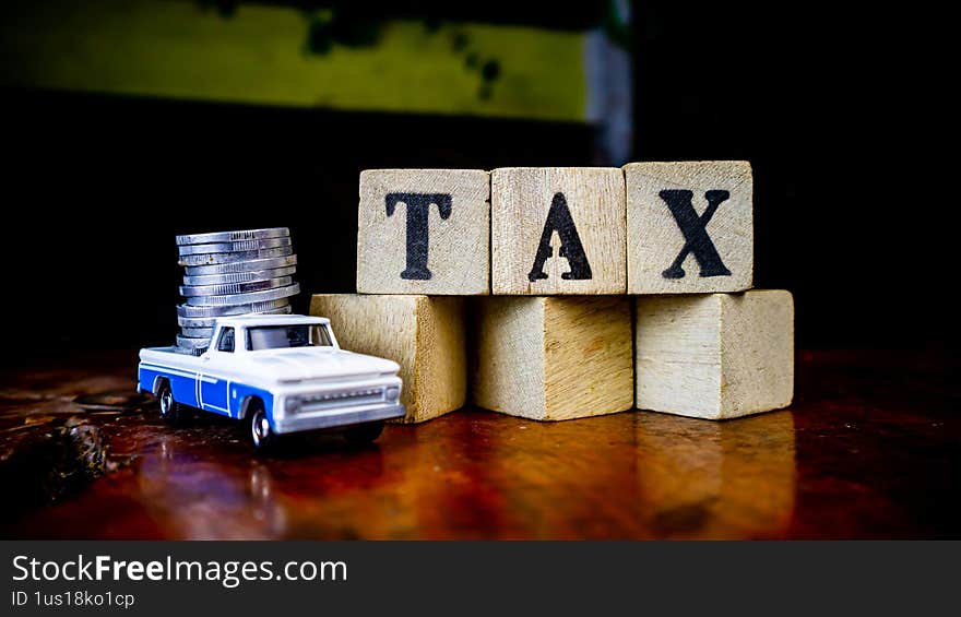 tax writing on wood with coins on it and a toy car in the foreground