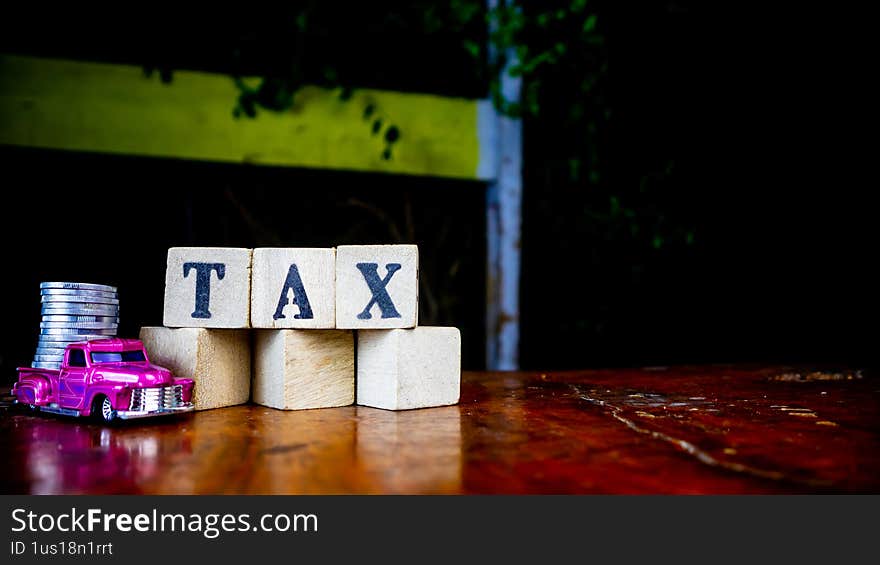 tax writing on wood with coins on it and a toy car in the foreground