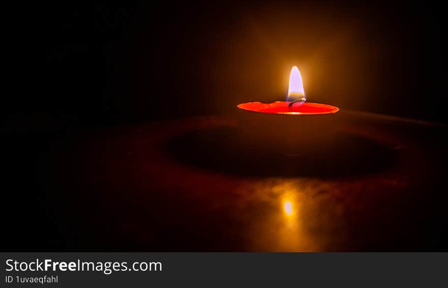 a burning candle against a dark background