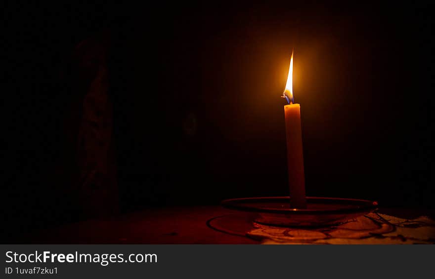 a burning candle against a dark background