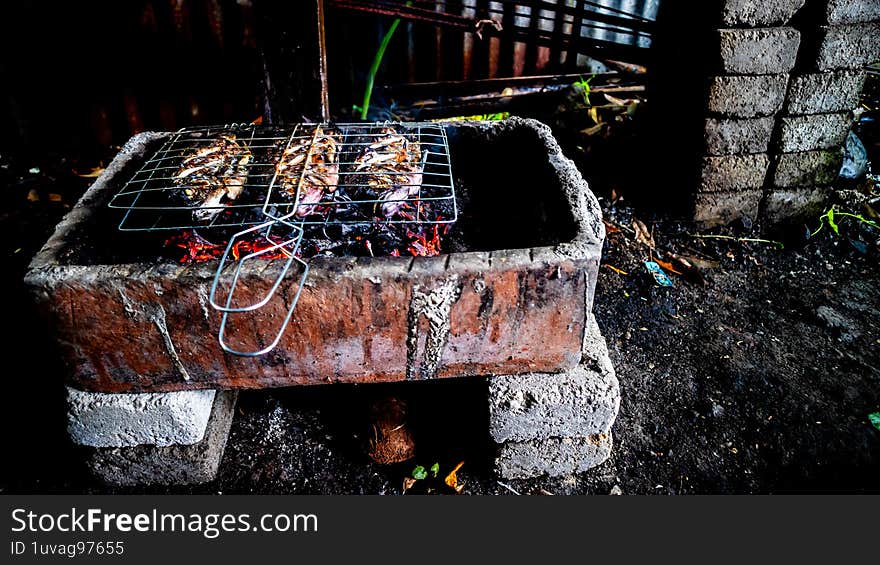 Tilapia fish being grilled on a traditional grill