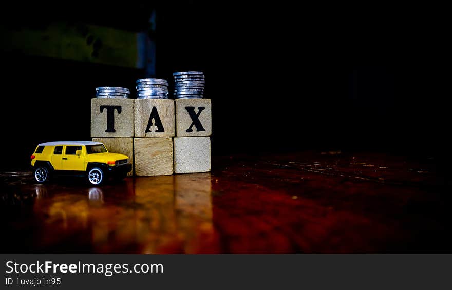 tax writing on wood with coins on it and a toy car in the foreground