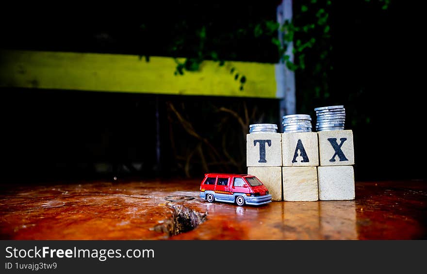 tax writing on wood with coins on it and a toy car in the foreground
