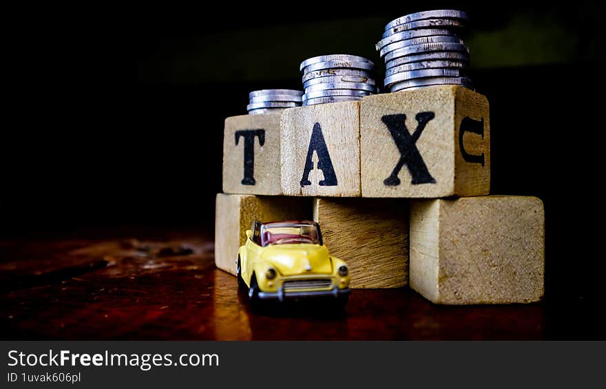 tax writing on wood with coins on it and a toy car in the foreground
