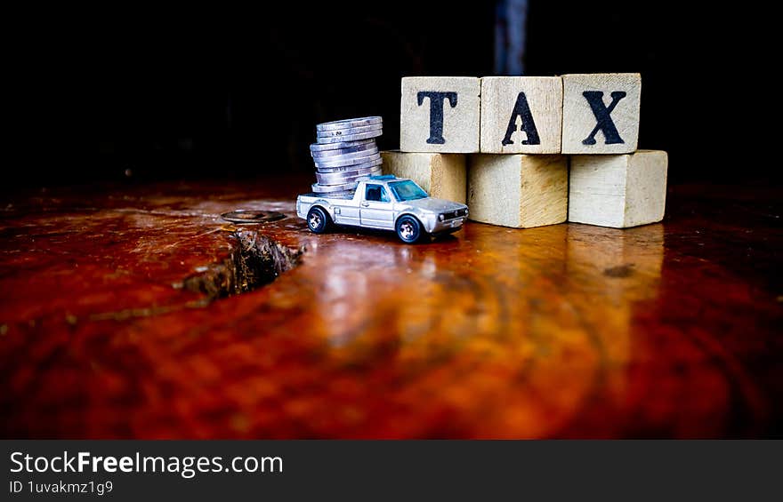tax writing on wood with coins on it and a toy car in the foreground