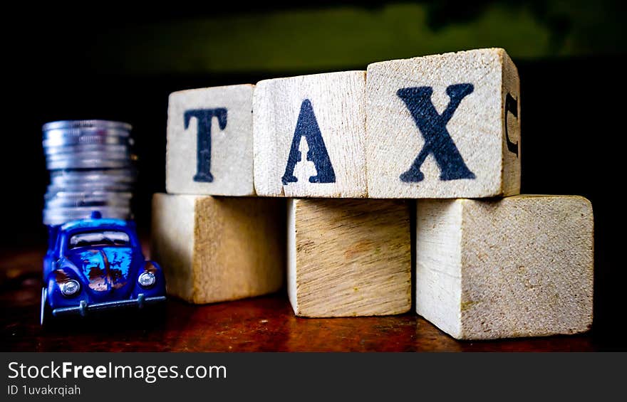 tax writing on wood with coins on it and a toy car in the foreground