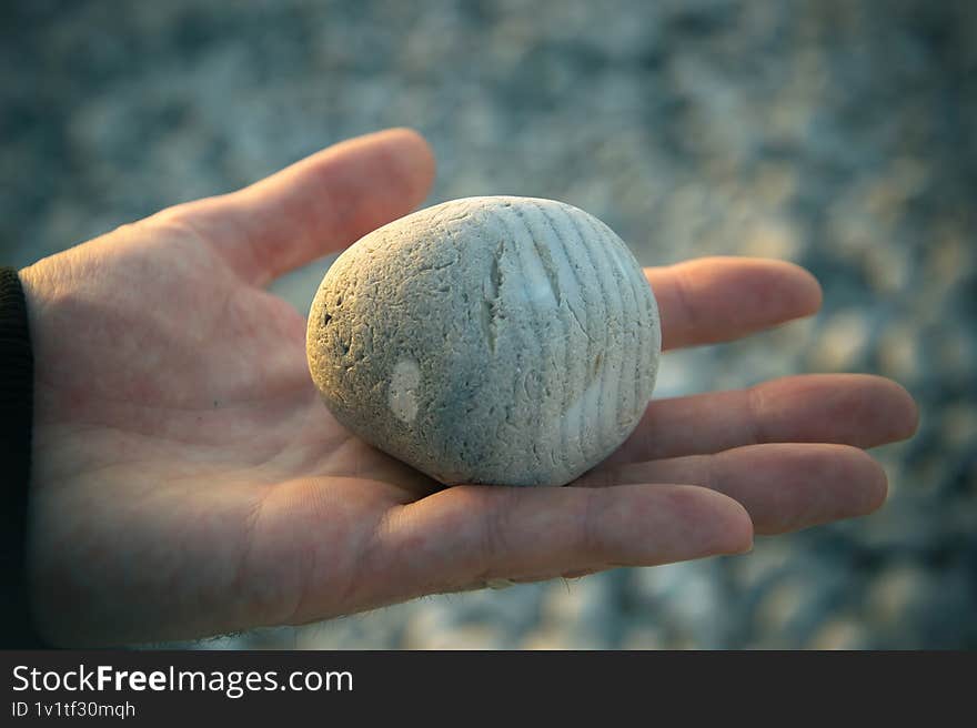 A round pebble stone on a mans palm