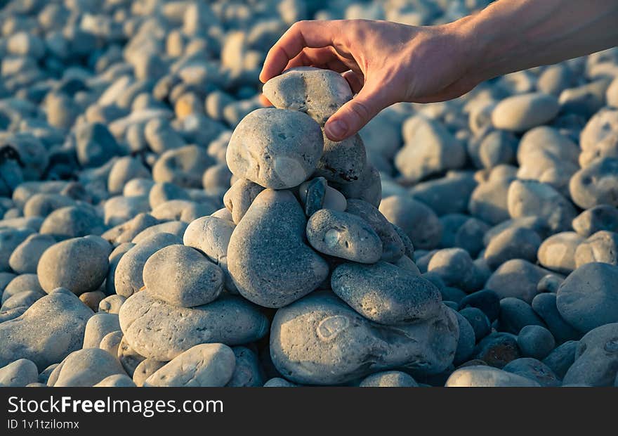 Hand building a tower of pebbles at the beach